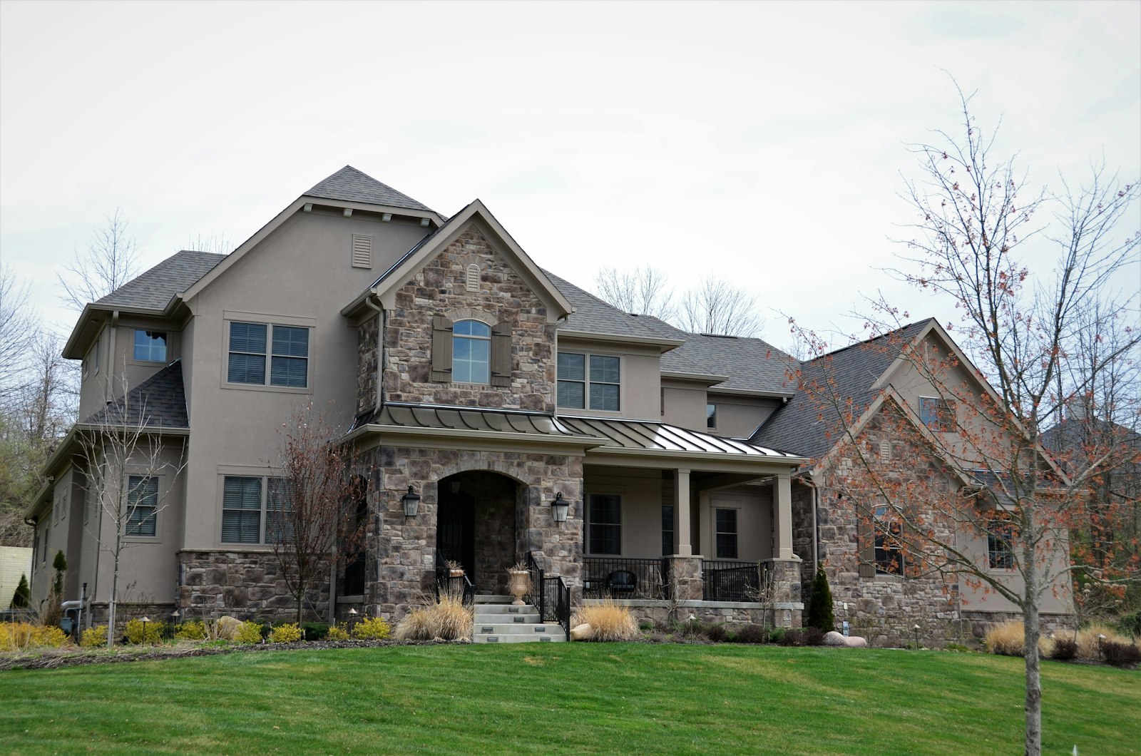 A large traditional stone and stucco luxury estate home with manicured lawn